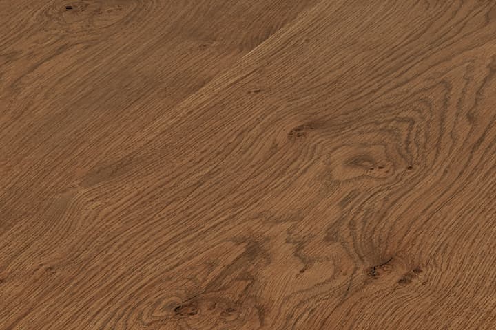 A wooden table features a natural, live-edge design with visible wood grains and knots, blending into a rustic, minimalist environment. The table has a finely sanded and polished surface.