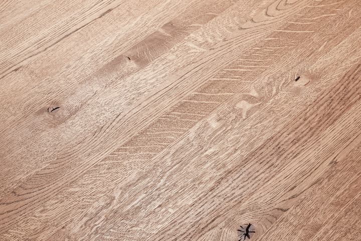 A wooden surface shows detailed grain patterns and natural imperfections, including knots and lines. The wood appears polished and smooth, covering the entire frame without any additional objects present.
