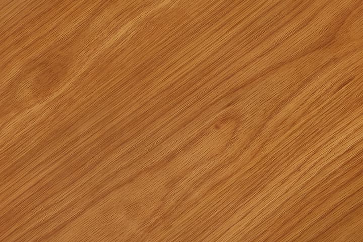 A rectangular wooden tabletop with a smooth, light brown surface partially extends over a white background, showing part of a leg in the bottom left corner.